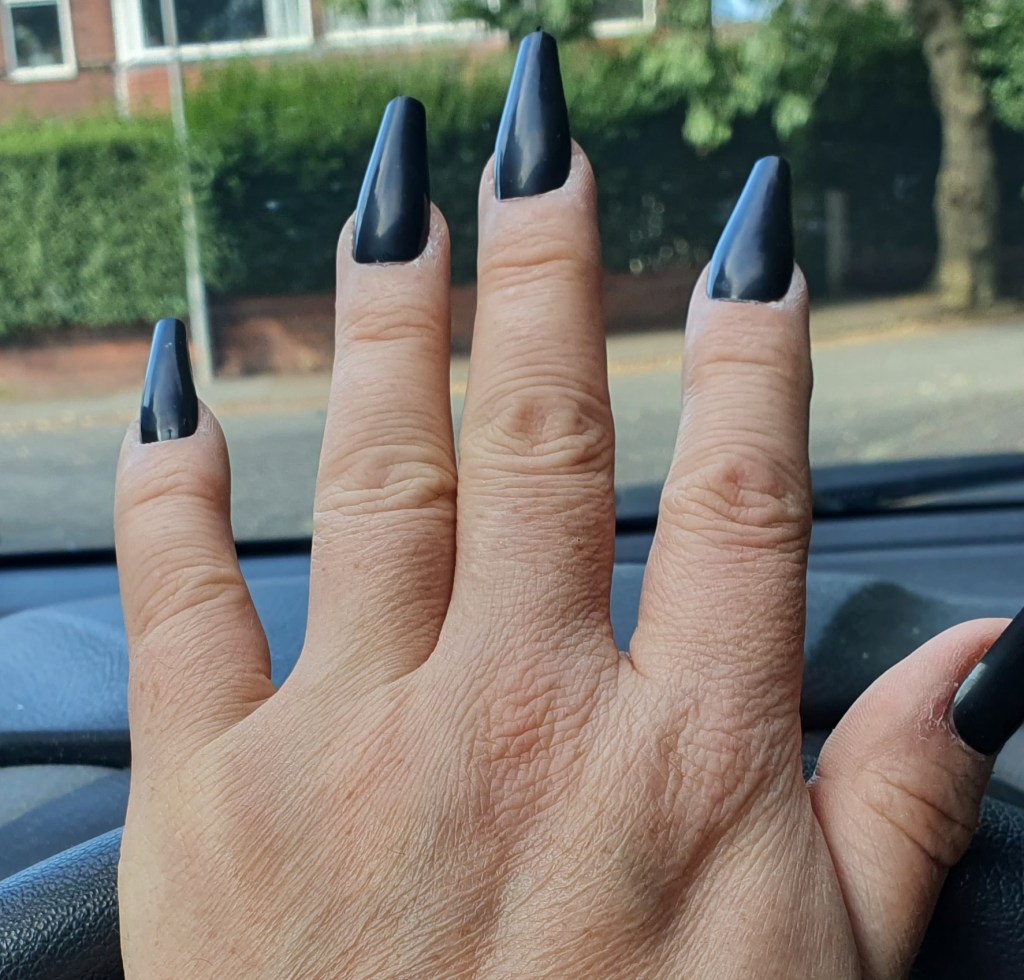 Hand showing long black “coffin-style” acrylic nails